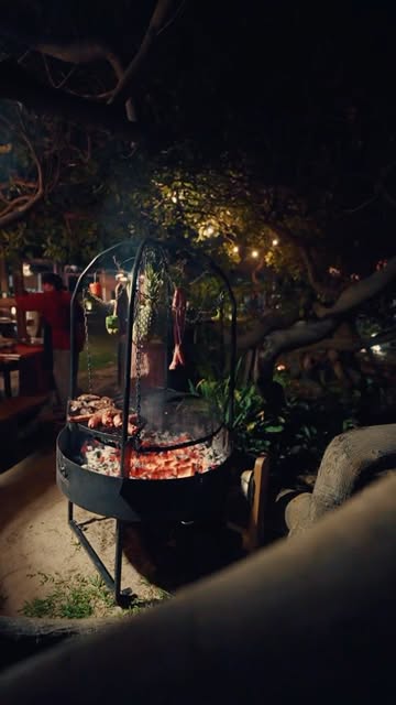 Parrilla acesa à noite no jardim do Okarú